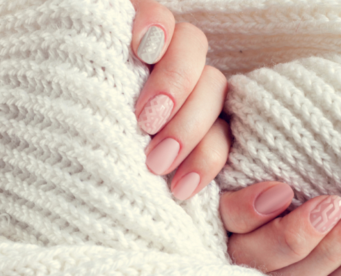 Frauenhände mit Knit Nails und Schal